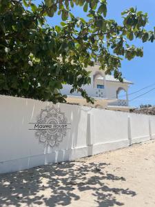 Una cerca blanca con un cartel que lee Casa Kulum en Mauwa House, en Paje