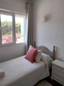 Schlafzimmer mit einem Bett mit einem rosa Kissen und einem Fenster in der Unterkunft Bellavista Bolonia in Bolonia