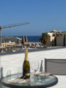 Luxury Penthouse in Sliema في سليمة: زجاجة من النبيذ موضوعة على طاولة مع أكواب