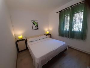 ein Schlafzimmer mit einem weißen Bett und einem Fenster in der Unterkunft HOUSE-APARTMENTS ELA -MIRCA- FAMILY HOLIDAY in Mirce