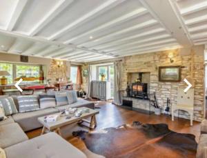a living room with a couch and a stone wall at Luxury Country Cottage With A View in Enstone