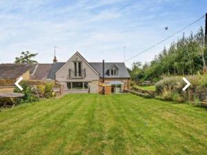 ein Haus mit einem großen Garten davor in der Unterkunft Luxury Country Cottage With A View in Enstone