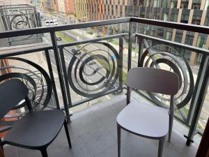a balcony with two chairs and a view of a street at COMFORT Apartment Pawia street - free parking !!! in Krakow