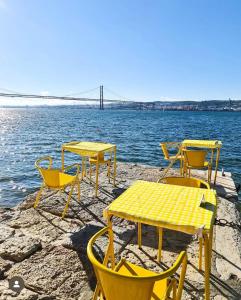 a group of tables and chairs next to the water at Golden Place - Cacilhas in Almada