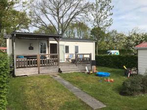 a tiny house with a porch and a deck at Luxe 4-persoons chalet zon zee strand Renesse. in Renesse