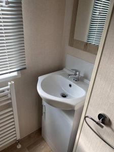 een badkamer met een witte wastafel en een spiegel bij Luxe 4-persoons chalet zon zee strand Renesse. in Renesse