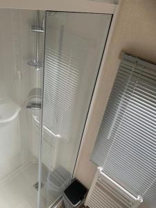 a glass shower in a bathroom with a window at Luxe 4-persoons chalet zon zee strand Renesse. in Renesse