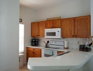 a kitchen with wooden cabinets and a white microwave at Enchanting Escape 3 Bedroom Minutes from Disney! in Kissimmee