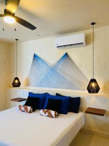 1 dormitorio con cama blanca y almohadas azules en Sunsteps suite pyramids, en Isla Holbox