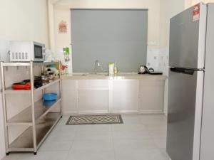 cocina con armarios blancos y nevera de acero inoxidable en Rafflesia Two Bedroom Pool View, en Kampong Tanah Merah