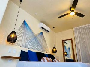 1 dormitorio con 1 cama con almohadas azules y ventilador de techo en Sunsteps suite pyramids, en Isla Holbox