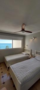 een slaapkamer met 2 bedden en een plafondventilator bij FirstLine BeachView in El Campello