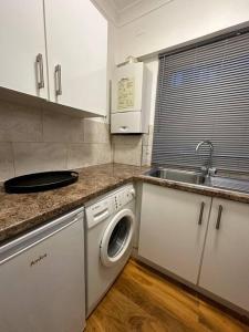 a kitchen with a sink and a washing machine at Edgware Road Large Ground Floor Studio in London