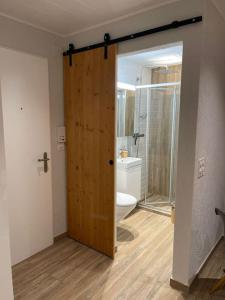 uma casa de banho com uma porta de madeira que leva a um WC em Kleines Bijou in Klosters Platz em Klosters