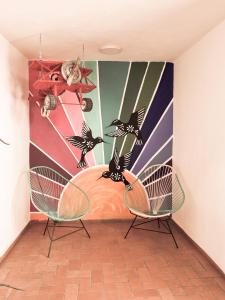 チョルーラにあるSanta Josefita B&Bの椅子2脚と壁画のある部屋