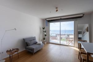 ein Wohnzimmer mit einem Stuhl und einer großen Glasschiebetür in der Unterkunft La Panoràmica del Mar in Tarragona