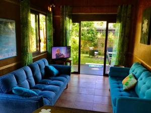 uma sala de estar com sofás azuis e uma televisão em Faré Luciana Moorea em Moorea
