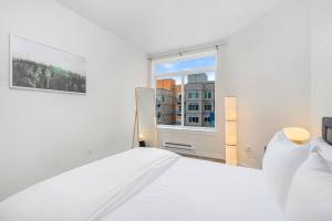 a white bedroom with a white bed and a window at Needle's Edge - 99 Walkscore! in Seattle