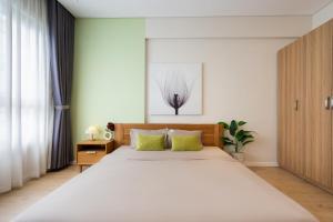 um quarto com uma grande cama branca com almofadas verdes em Diamond Island Highfloor RiverView 8min to D1 em Ho Chi Minh