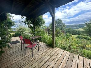 una terraza de madera con 2 sillas y una mesa en Au mont des Brumes, en Stoumont