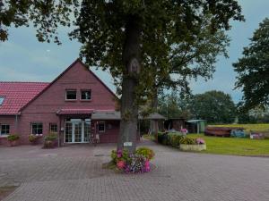 a tree in front of a pink house with flowers at Ferienwohnung JAGODA in der Lüneburger Heide in Frankenfeld