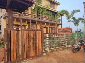 una casa con una puerta de madera y una motocicleta aparcada delante en Khoai Village Resort en Shānti Niketan
