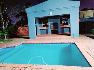 a swimming pool in front of a blue building at Maison Akiba in Pretoria