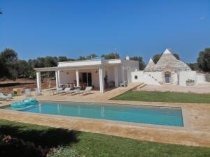 uma villa com piscina em frente a uma casa em Trullo EVO con piscina privata em Ostuni