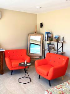 un soggiorno con 2 sedie rosse e uno specchio di LE SEPT charmant studio aux portes des calanques a Cassis