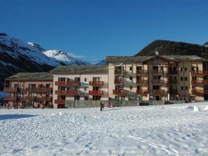 un grand bâtiment dans la neige devant une montagne dans l'établissement Appart cosy 4 pers, pied des pistes, wifi, garage à Val-Cenis - FR-1-508-261, à Termignon