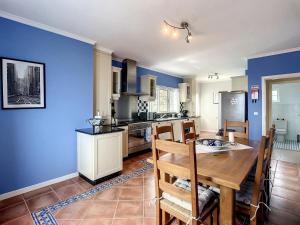 a kitchen with blue walls and a wooden table and chairs at Vinhaticos Villa by Atlantic Holiday in Porto Moniz