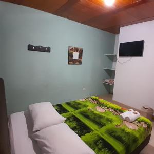 a bedroom with a bed with a green blanket on it at Hostal Johnnier in Salento