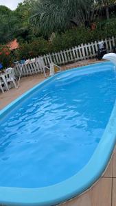 a large blue swimming pool next to white chairs at Casa de Japaratinga in Japaratinga