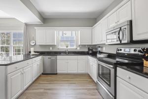Una cocina con gabinetes blancos y encimeras negras. en 214 Shoreland Home, en Gulf Shores