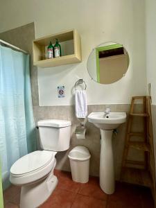 a bathroom with a toilet and a sink and a mirror at Hotel Zelen in Tamanique