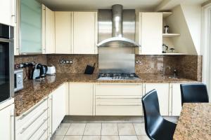 a kitchen with white cabinets and granite counter tops at Kensington Skyline Penthouse in London