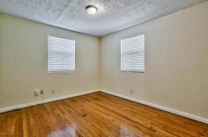 6515 Bartholf Ave في جاكسونفيل: غرفة فارغة بها نافذتين وأرضيات خشبية