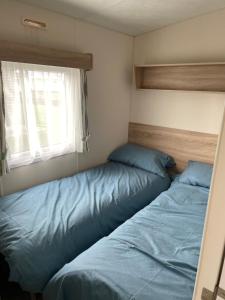 a bedroom with two beds and a window at Emeralds caravan lettings in Selsey