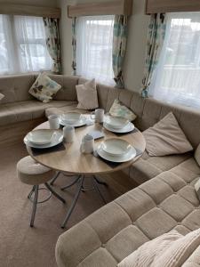 uma sala de estar com uma mesa e um sofá em Emeralds caravan lettings em Selsey