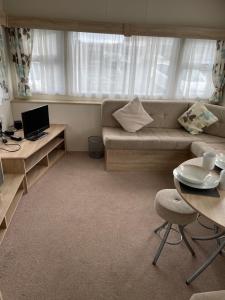 a living room with a couch and a table at Emeralds caravan lettings in Selsey
