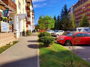 a red car parked on the side of a street at Apartman Lux in Covasna