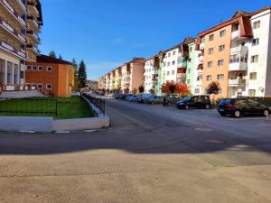 an empty city street with parked cars and buildings at Apartman Lux in Covasna