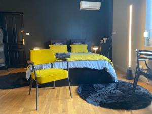 a bedroom with a bed and two yellow chairs at Chambre marais in Écourt-Saint-Quentin