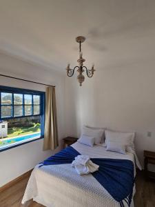 a bedroom with a bed with a blue blanket and a window at Casa da Tuta Pousada in Tiradentes