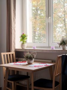 d'une table, de deux chaises et d'une fenêtre ornée de plantes. dans l'établissement Cozy Warsaw City Center Studio, à Varsovie