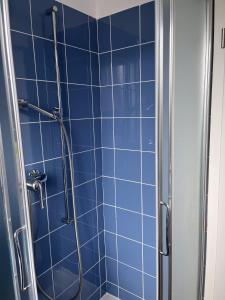 y baño con ducha de azulejos azules. en B&B Cloè, en Pregassona