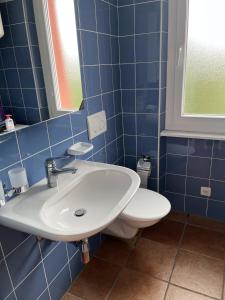baño de azulejos azules con lavabo y aseo en B&B Cloè, en Pregassona