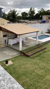 a pavilion with a table and a swimming pool at POUSADA RECANTO DULE in Guarapari