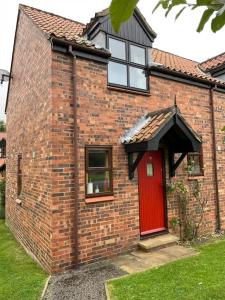 a brick house with a red door and a window at Runaway Cottage, Whitby in Whitby