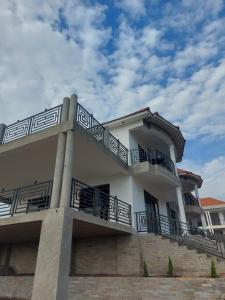 a large white building with balconies and stairs at Freeve Suites Akright City Bwebajja in Buzzi